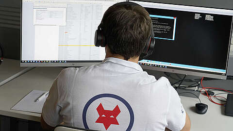 Q-FOX Mitarbeiter mit Headset sitzt an seinem Computer und bearbeitet IT-Service-Anfragen