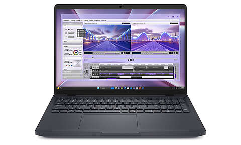 Auf einer weißen Fläche steht ein geöffneter schwarzer Laptop, auf dessen Bildschirm eine Videobearbeitungssoftware mit Aufnahmen einer Brücke sowie verschiedenen sichtbaren Bearbeitungswerkzeugen und Zeitleisten angezeigt wird.